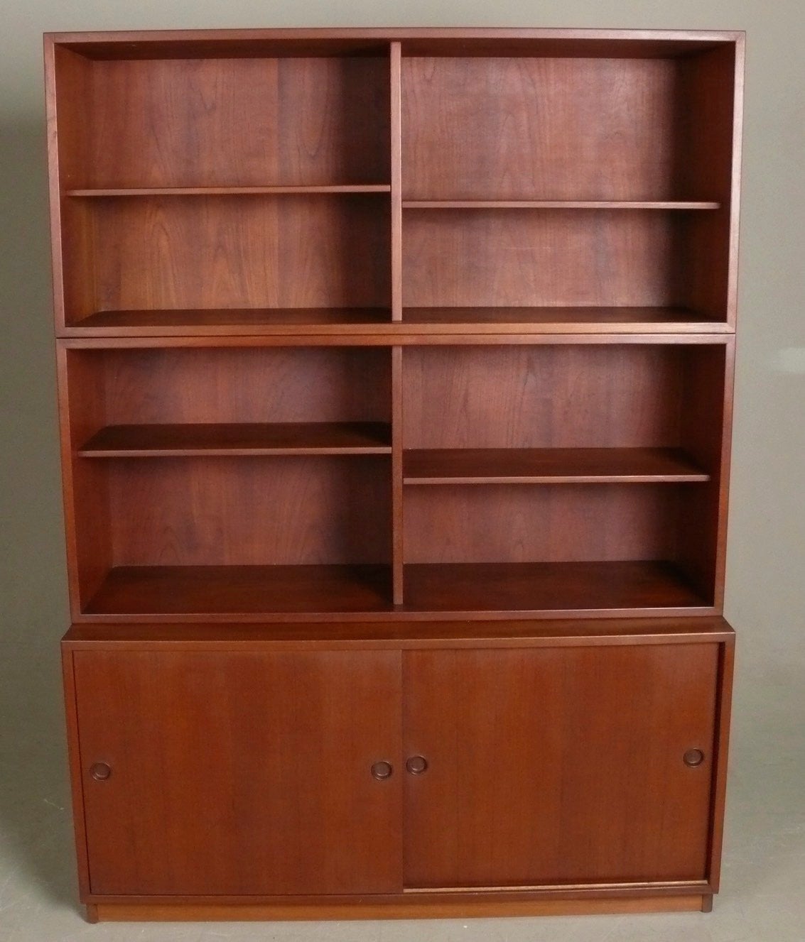 C. 1960 teak, 3-piece cabinet by Borge Mogensen, Denmark. One adjustable shelf behind each sliding door in lower section and 6 adjustable shelves in upper bookcase section. Signed with makers name on reverse.