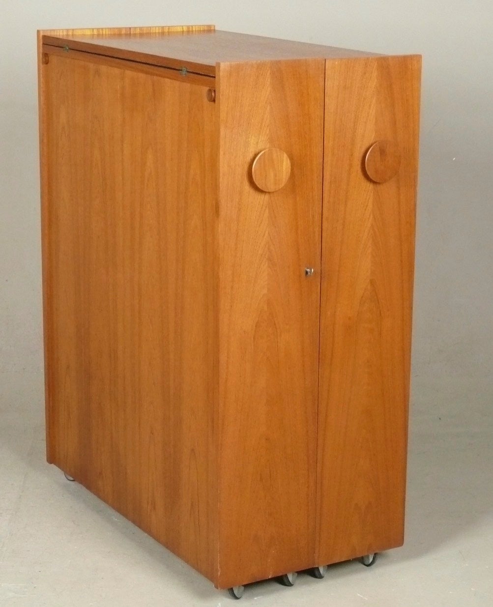 1960s rolling teak cocktail cabinet or serving bar from Denmark designed by Erik Buck. For daily use, it's an unassuming rolling and locking cocktail cabinet with lots of storage for liquor and glassware. When you have a party, you can open it, flip