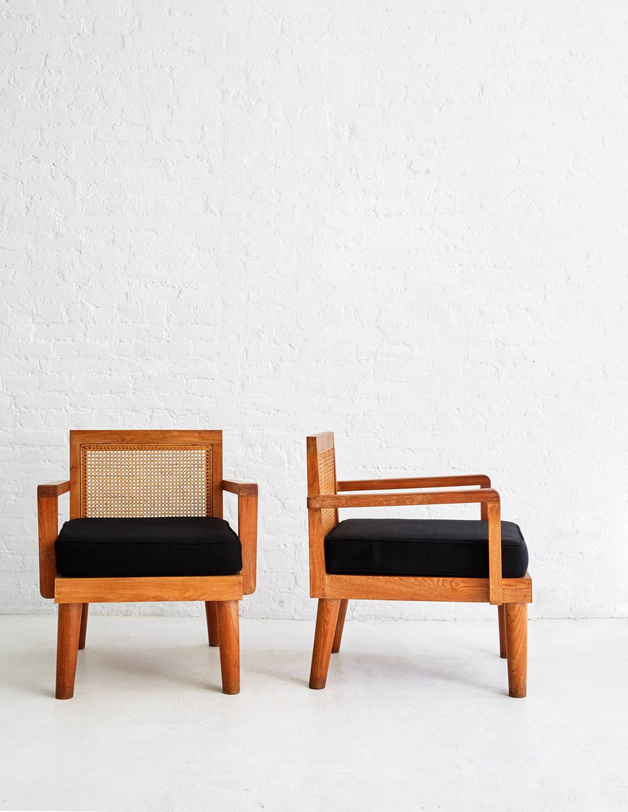 Unique pair of French teak and cane lounge chairs with red upholstered seat. 

Beautiful legs á la Charlotte Perriand and caning reminiscent of Pierre Jeanneret. 

c. 1950s.