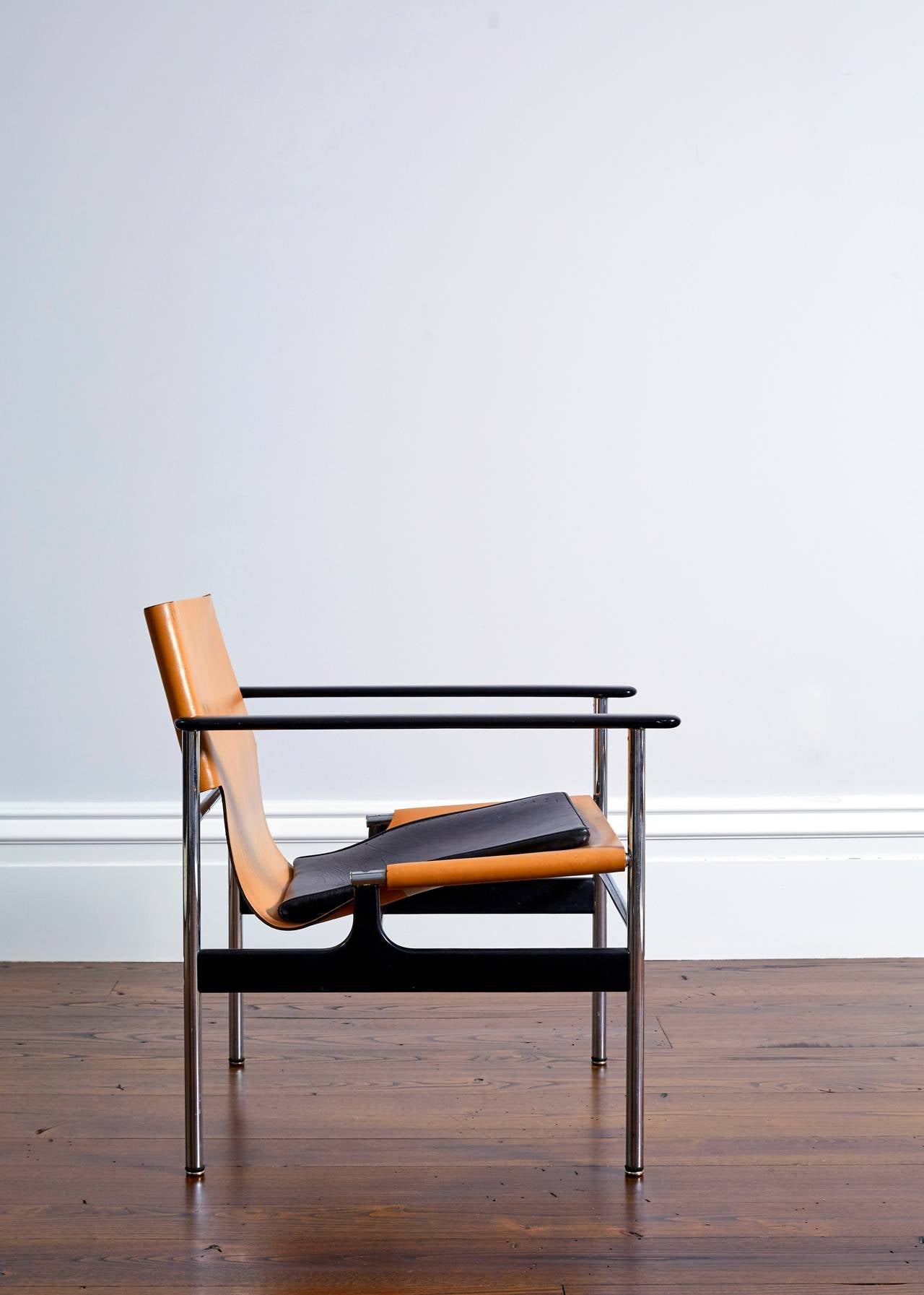Charles Pollock's tubular steel frame sling chair with thick saddle leather chair and a foam rubber cushion covered in black leather.
