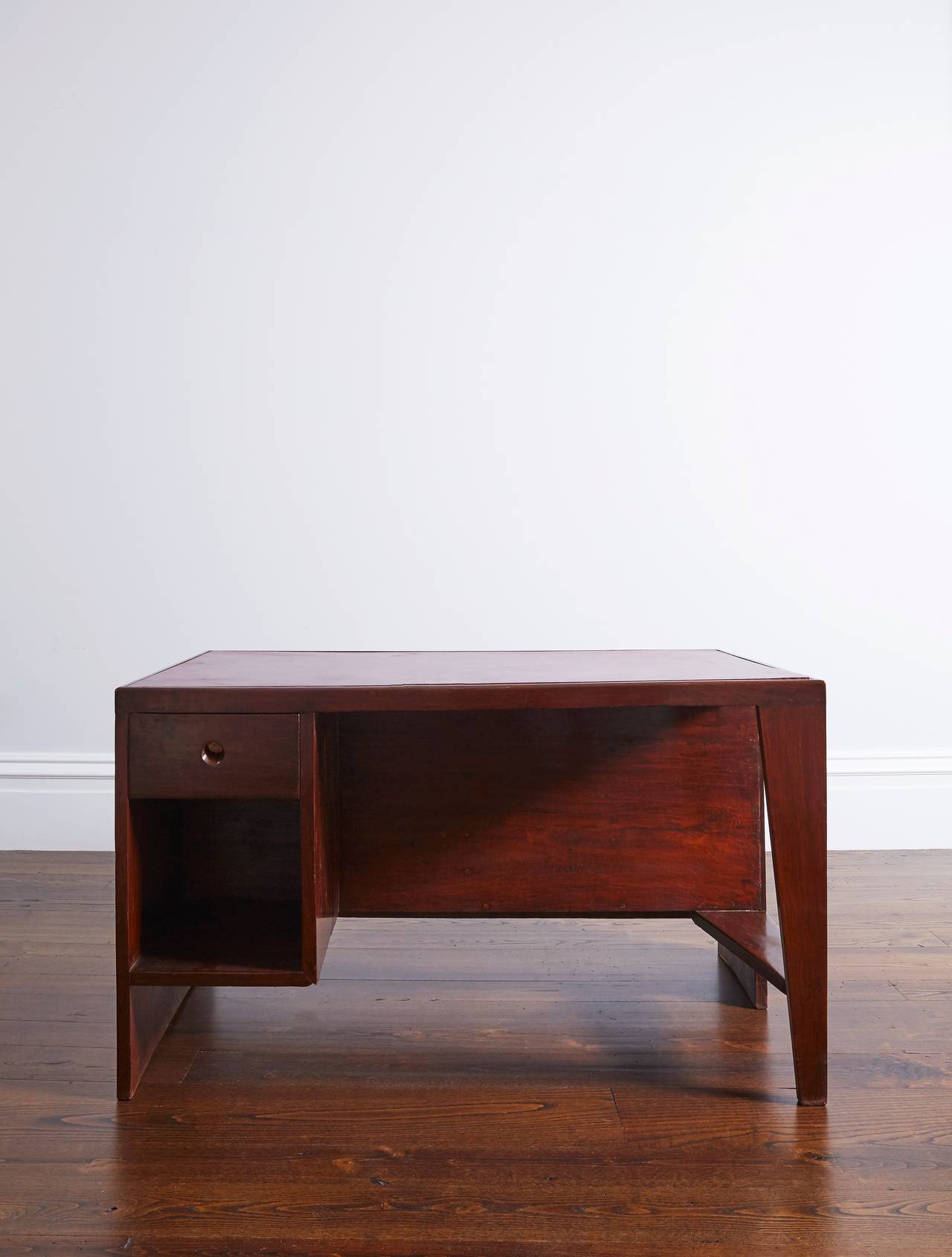 Stunning solid sisso (Indian rosewood) desk by Pierre Jeanneret from Chandigarh, circa 1957-1958. 

Tabletop fixed on a spindle leg and a solid block. On the user's side a drawer unit with an aluminum bottom and six open cabinets on the