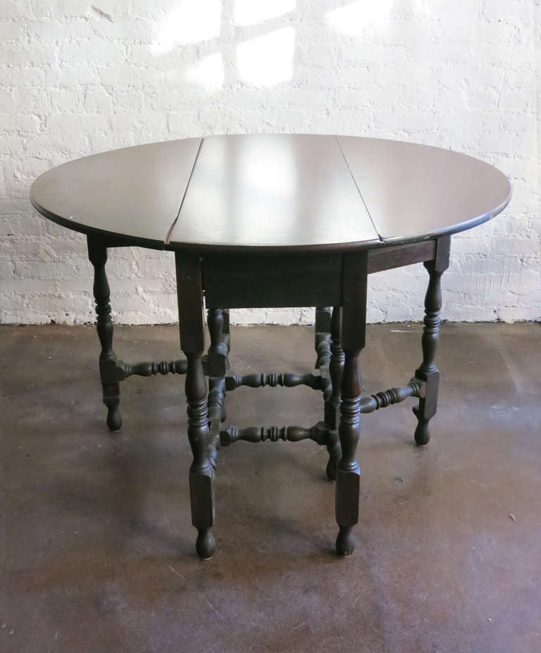 Stunning round drop-leaf table with turned legs.