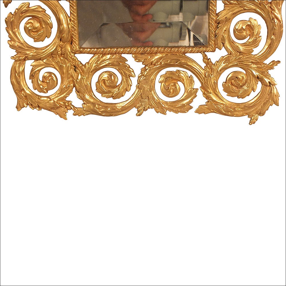 This pair of 19th century French Empire-style wall mirrors feature ornate bronze frames. The frames have recently been gold-plated and feature a Roman goddess motif atop a swirled, intricate frame. Inside the frames there is a new 1 inch beveled