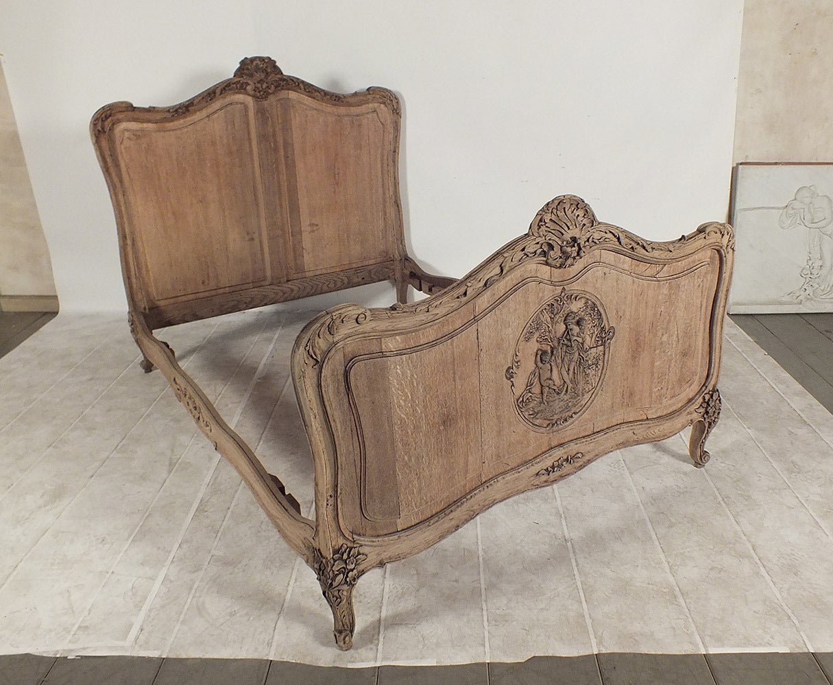 This is a beautiful 1900s French full size bed frame in Louis XVI-style. Made from solid oak wood in its natural wood state finish. Has wonderful carvings all throughout the frame of, flowers, leafs, crest and a scene of a women and children on the