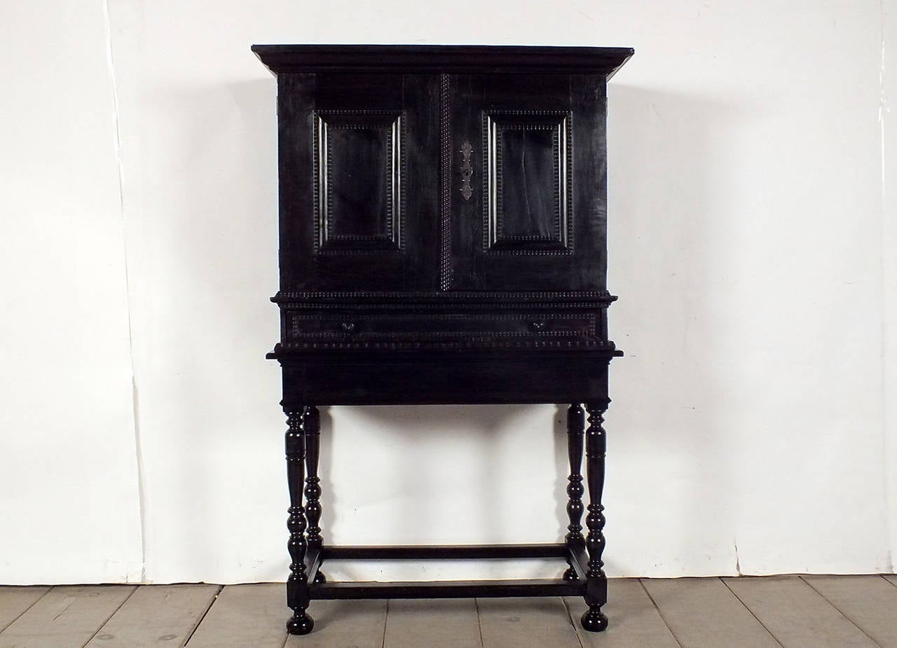 Rare 19th century Dutch ebonized cabinet with stand. This cabinet has been finished in a rich black color from the outside. Has two top door with one long keyhole key and lock are in good working condition, the bottom has one long drawer with Dual
