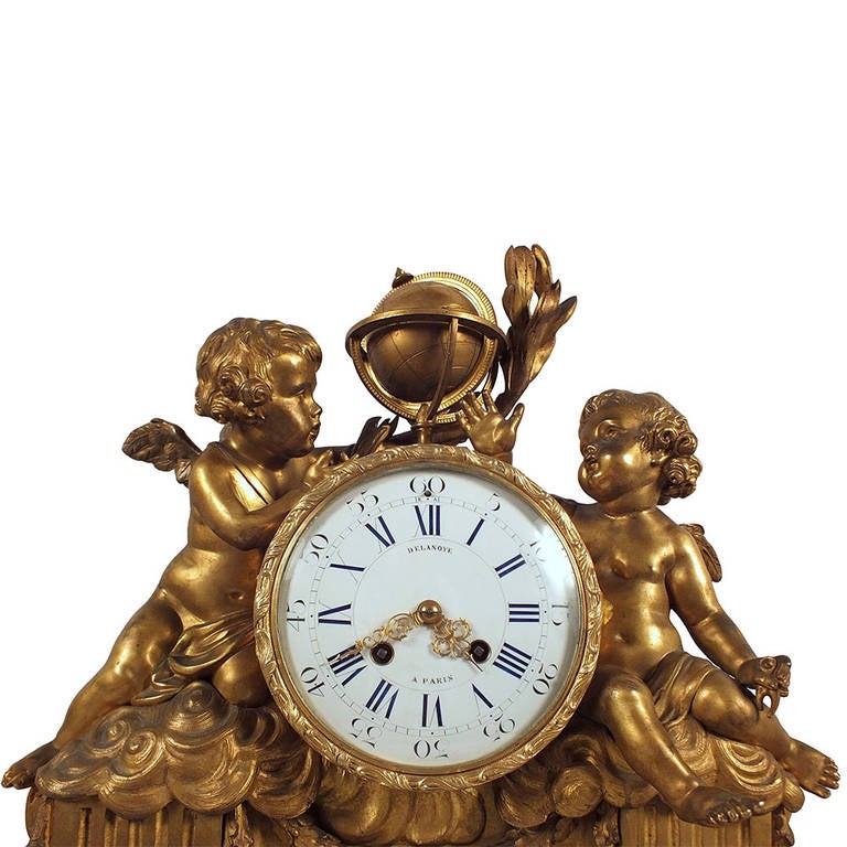 This exquisite Late 19th century mantel clock features an elegant white marble base with floral motif bronze accents and two bronze cherubs looking at an Atlas glove sitting on clouds sitting upon architectural column bases. This desk clock also