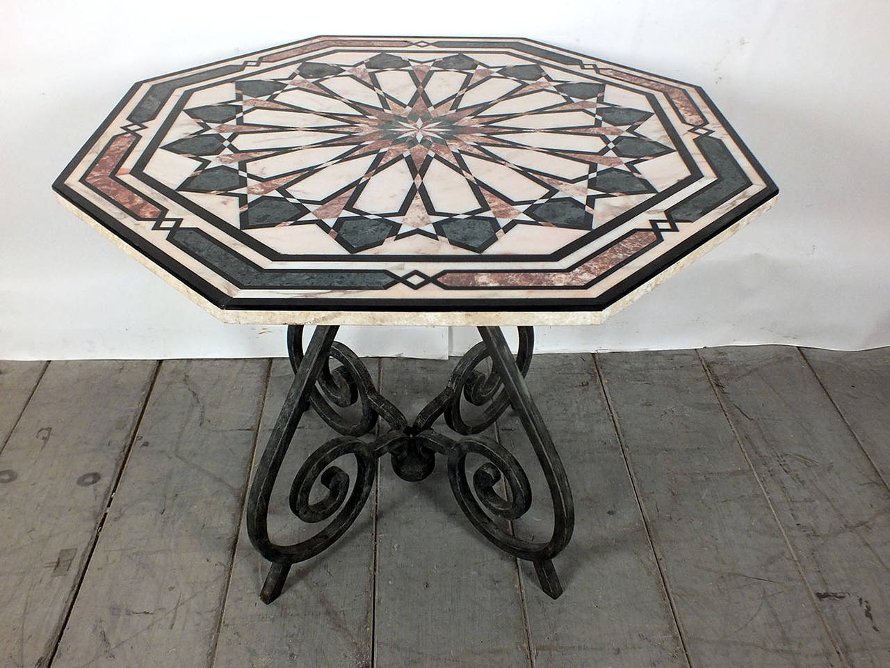 This is a 1970s Vintage Italian-style centre table that features a beautiful inlaid design upon the octagon shaped marble top. The iron pedestal legs have a scrolling design finished in a rustic color. Table is strong and sturdy ready to be used and