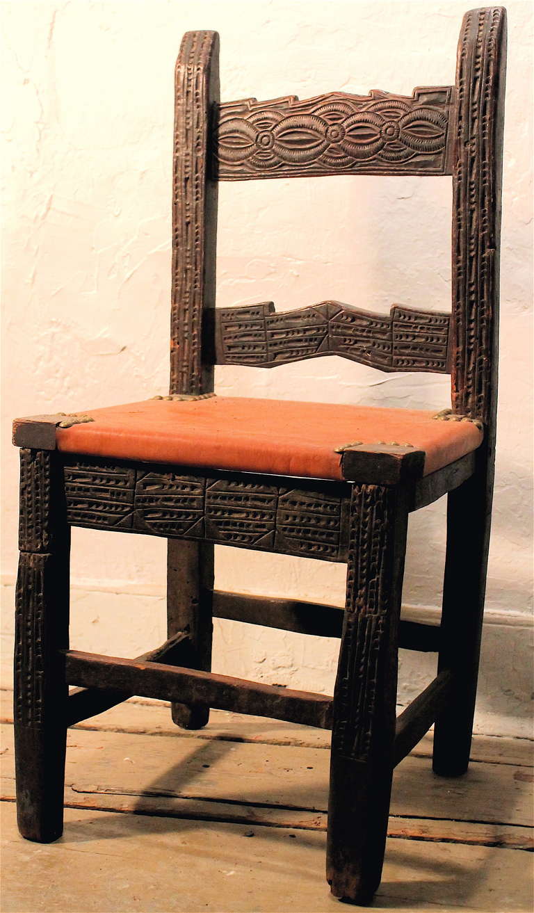 A small very old chair.  Carved with a rich dark patina. New leather seat.