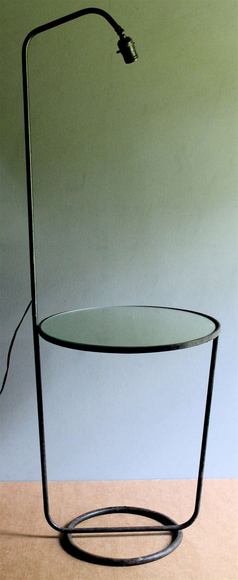 A combination floor lamp and a round mirror surfaced side table.  Original black paint.  No shade. The vertical tube detaches just below the wires exit hole.  Appears to be old if not original wiring.