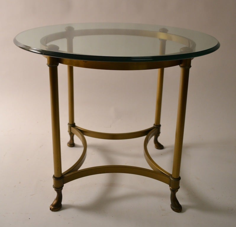 Pair round tables with thick plate glass tops, and brass bases.