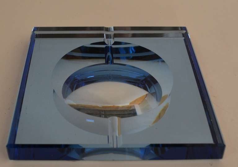 Thick blue glass with mirrored base, geometric cut circular bowl, with cigarette rest troughs. This item was made in Italy, and were sold through high end retailers such as Aspreys, in London.
