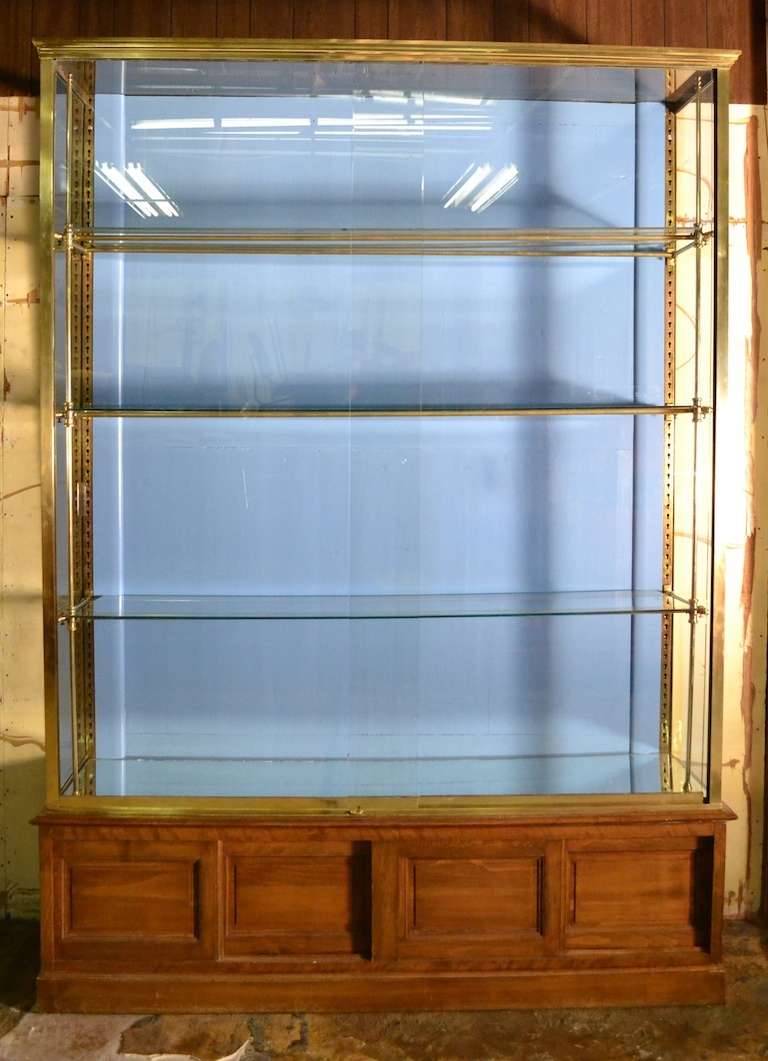 Wonderful large front opening French Vitrine. This case has a squared brass glass with two sliding glass doors, and adjustable glass shelves (3) The glass shelves rest on a tubular brass  structure, the whole of which rests on a solid wood base,