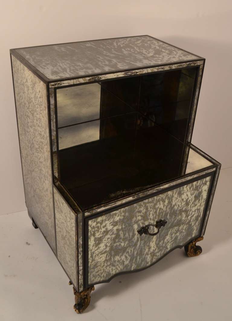 Glamorous marbleized  mirrored surfaces with black trim. One ll large drawer and an open cubby space.