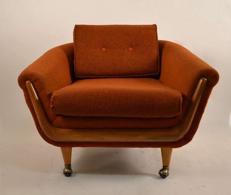 Swanky lounge in burnt orange tweed, with exposed wood trim on rolling ball caster feet. Clean, original and ready to use condition. Attributed to Adrian Pearsall for Craft Associates.
Depth in listing is seat depth.