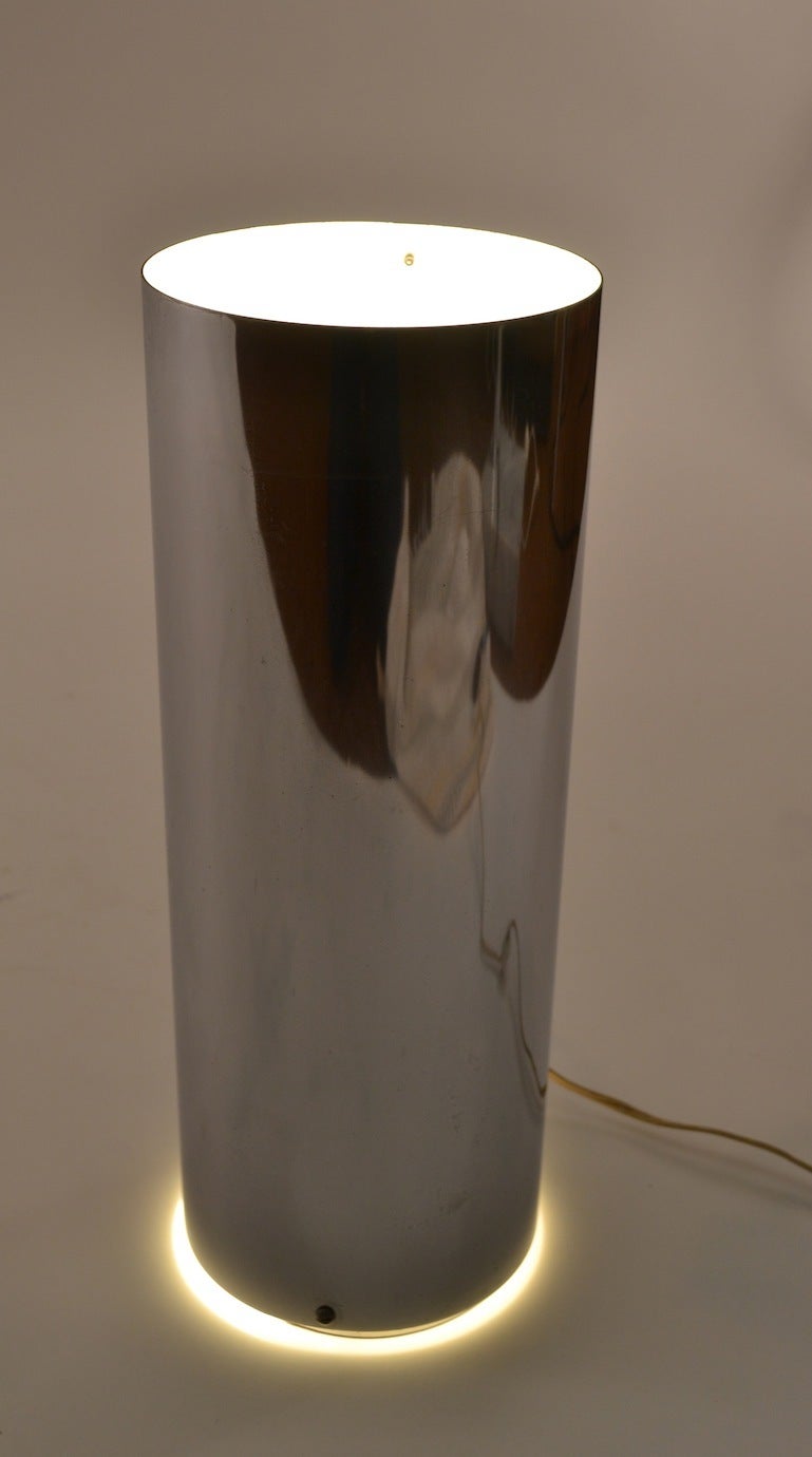 Indirect uplight chrome cylinder lamp, with opening at the base to illuminate up and down.