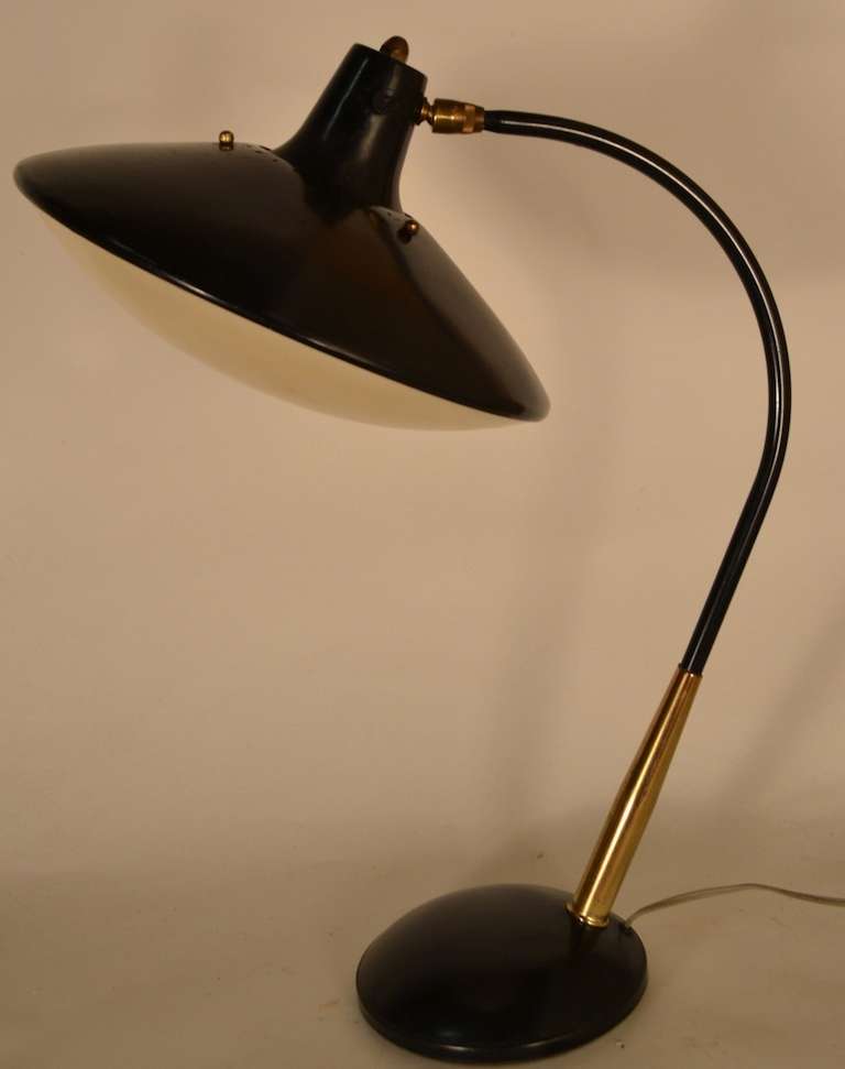 Elegant desk lamp, with adjustable swivel and tilt disk form shade. This lamp still retains the original plastic disk diffuser, and is in original finish, and working.