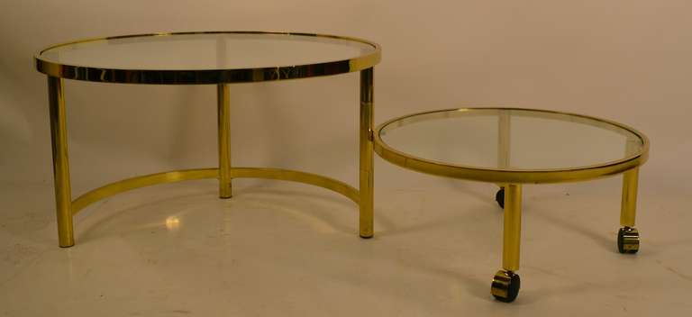 Disk form table which opens to a two tier expanded coffee table size. Brass plated metal frame, with glass tops. Dimensions in listing are for the table in closed position, open L is 50