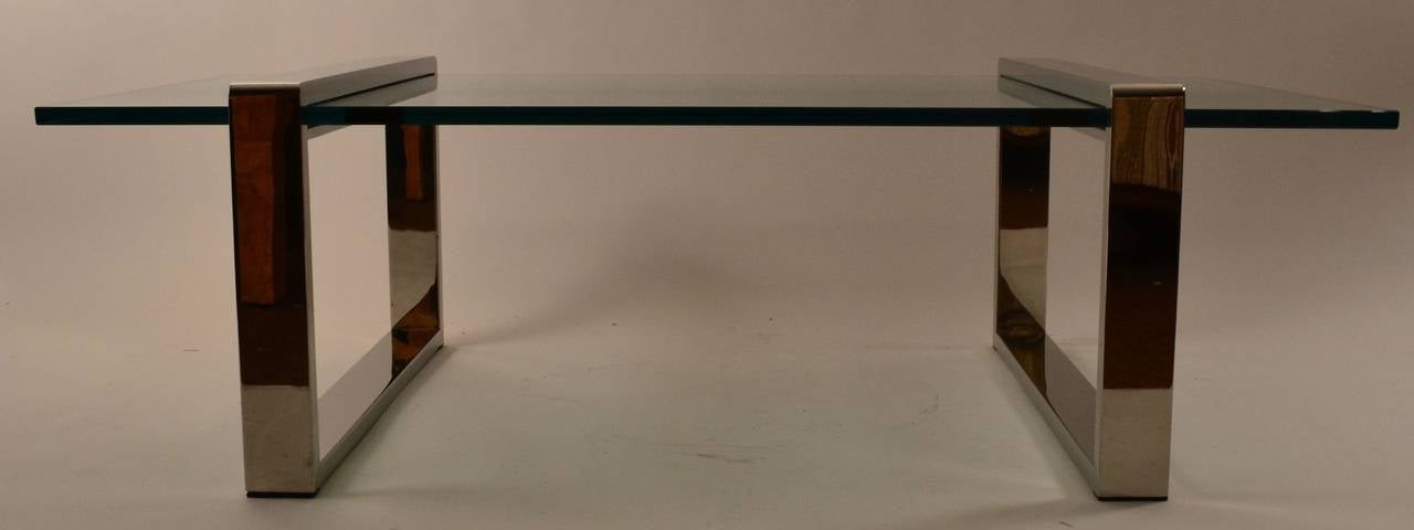 Les pieds en métal (nickel) en forme de boîte soutiennent le plateau en verre de 3/4