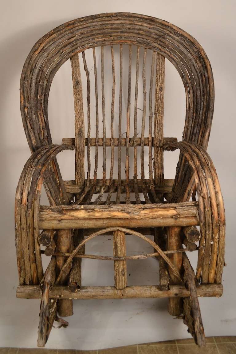 Rustic Adirondack rocker, made of bent twigs and sticks. Folky Americana porch rocker, charming and comfortable.