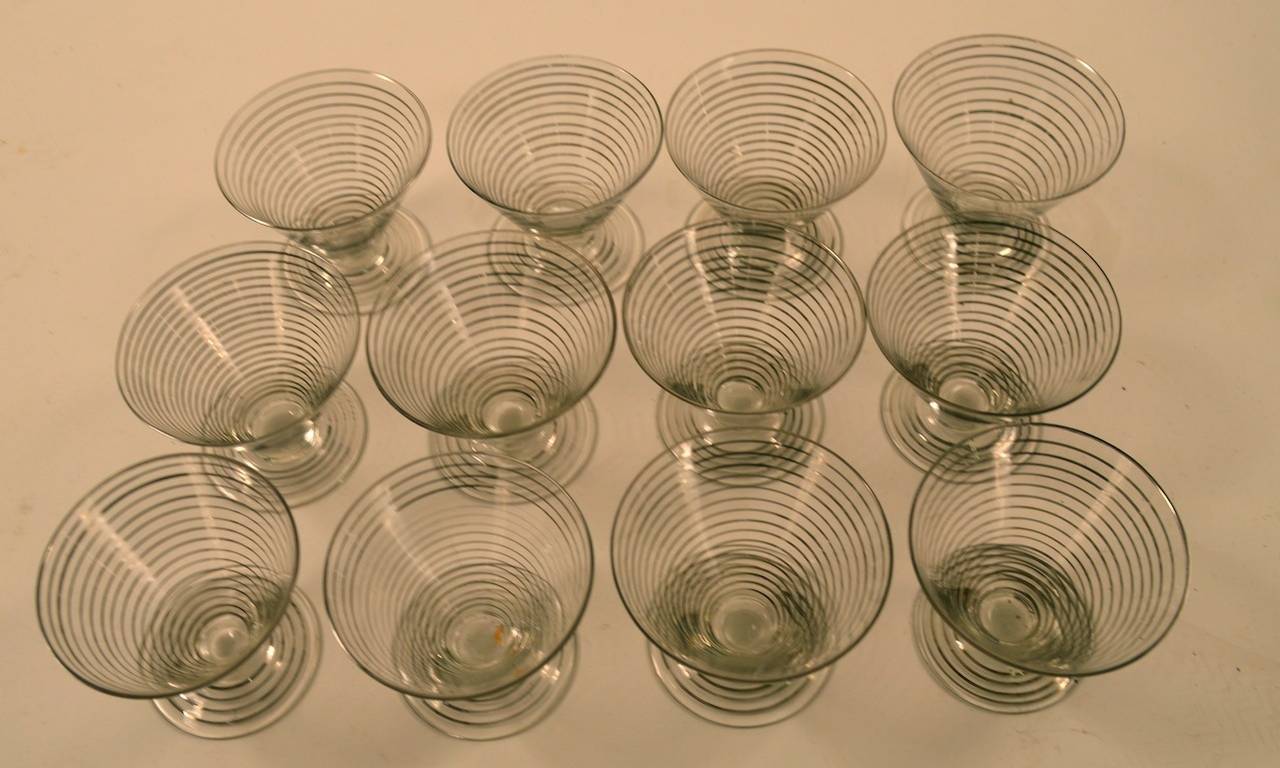 Cocktail shaker with twelve matching glasses. Silver band repeated rings motif, Art Deco cocktail set. A couple of the glasses have tiny flakes at the top edge, most are perfect. The glass is paper thin, and unusually fine.   Dimensions in listing