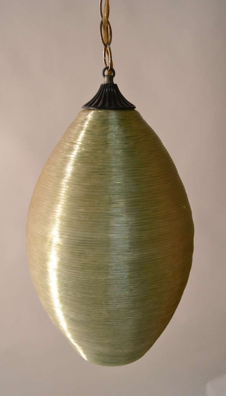 The textured spun fiberglass surface appears to be crystal color, but since the interior is green, it turns florescent green when light. Come with very long chain as these were usually hung as a 