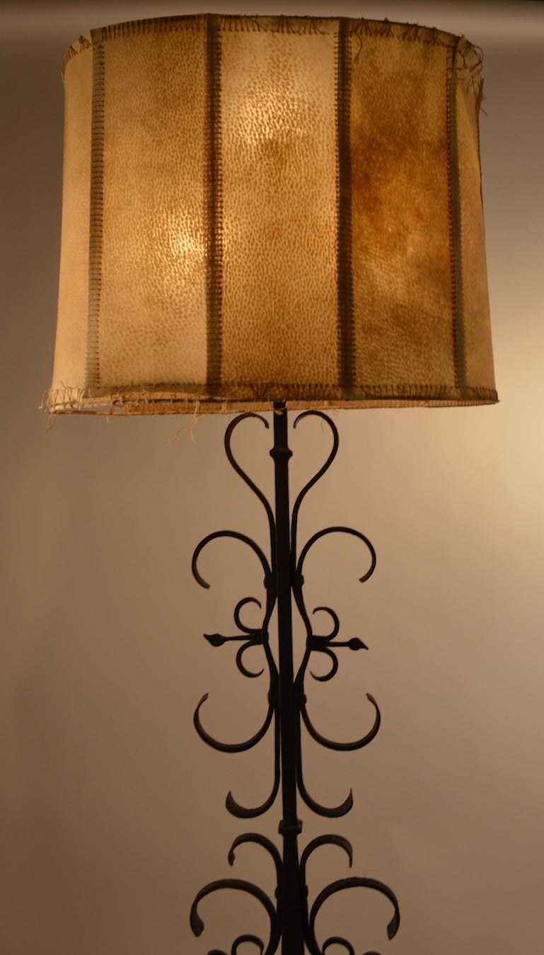 Great quality metal work, hand wrought iron floor lamp, with original hyde shade ( shade shows wear ) Three bulbs at top can be used as a single light, or three bulbs can be lit simultaneously for greatest light. Spanish, Gothic, and Arts and Crafts