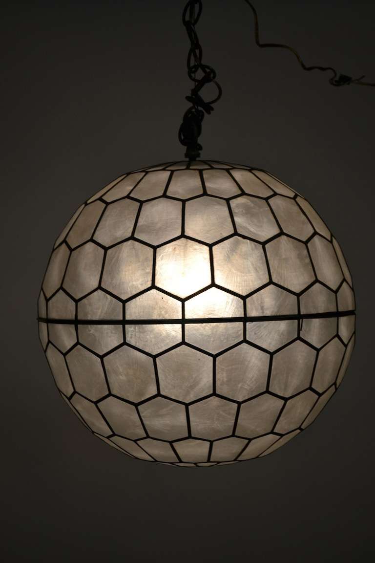 Architectural ball form chandelier made of  segmented panels of capiz shell. Fixture opens in the middle to accept bulb etc.