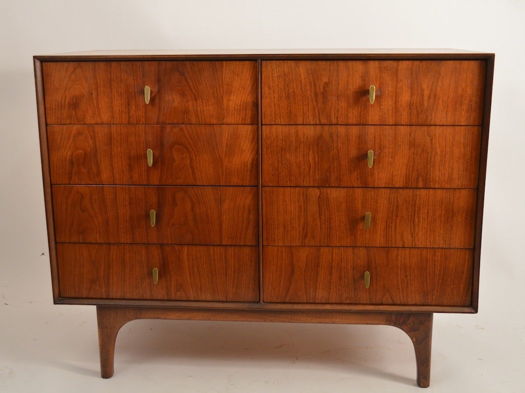 Eight drawer bachelors chest, figured veneer front with brass handles, on raised sculpted  legs. This dresser is one of a series or three we've listed. Please view the matching pieces if you need more cabinets.