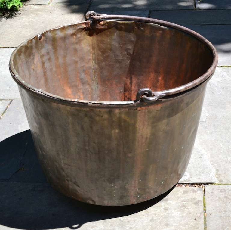 Large handmade copper bucket with hand wrought iron swing handle. Dovetail construction, American made antique pot which makes a nice log, or kindling wood fireplace accessory or place in the garden as sculptural decoration.