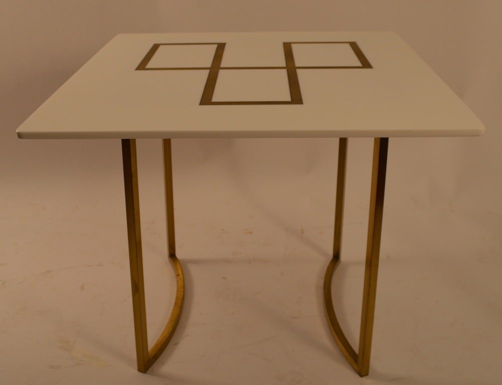 Intéressante table d'appoint, de lampe, d'extrémité, avec un épais plateau en verre blanc à surface géométrique dorée gravée, sur des pieds carrés en laiton. Probablement une production américaine des années 1960, d'après McCobb.