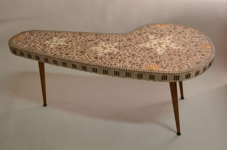 Fun tile top free form coffee table with tapered pole wood legs. The top incorporates three stars, and other interesting shapes, the edge is also fully tiled in the mosaic method. American made, California School Mid Century Modern period