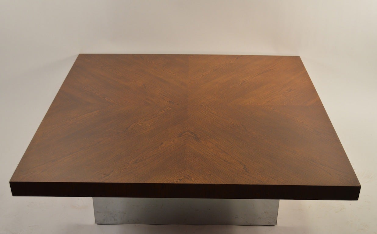 Square wood top rests on bright chrome square base to create a 