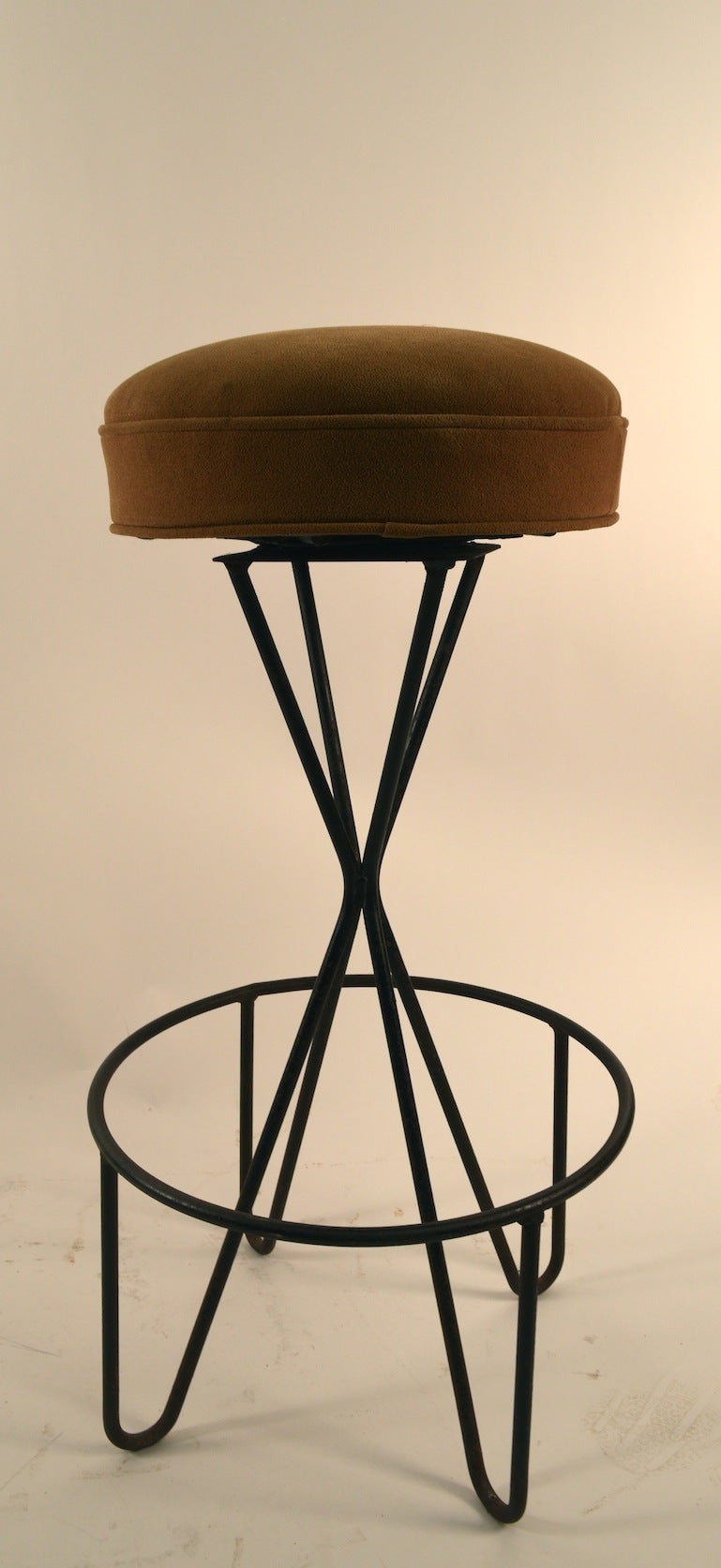 Four matching swivel stools designed by Paul Tuttle, wrought iron bases, with upholstered pad seat.