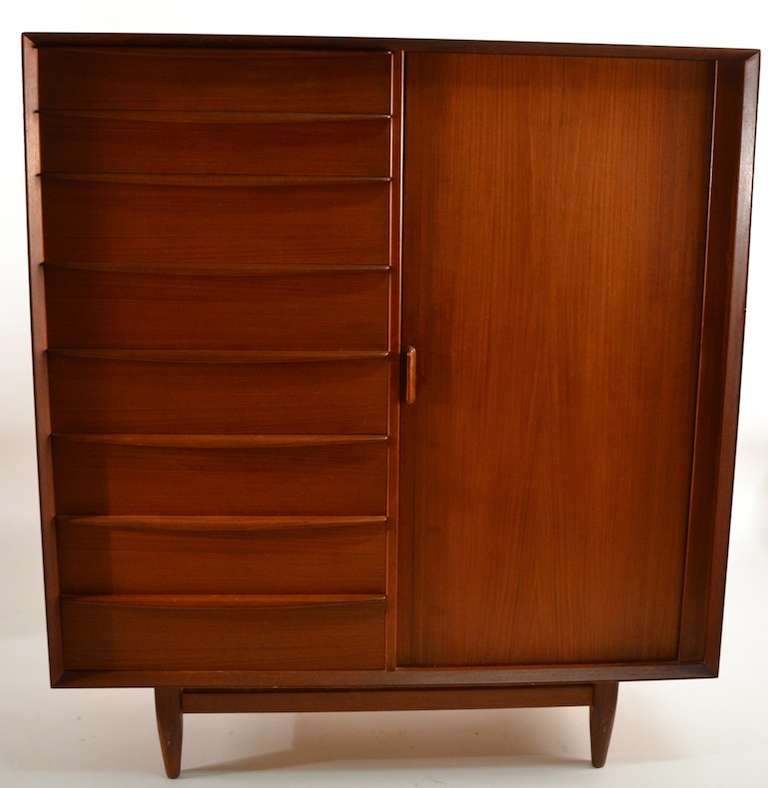 Falster teak chifferobe, wardrobe, armoire, one side has a tall bank of eight drawers, the other has a tambour roll door which opens to reveal interior with nine drawers, with blonde drawer fronts. This creates both a large amount of storage space,