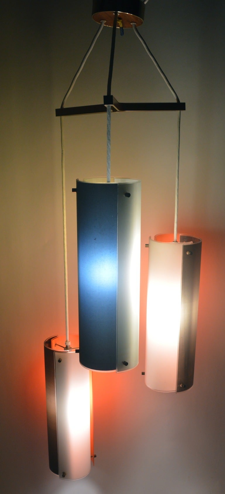 Interesting glass panel cylindrical form three light chandelier. probably Lightolier, after Ponti. Two cylinder shades have white, orange, and dark grey panels, one has yellow, white, and dark grey panels.  Each cylinder 18