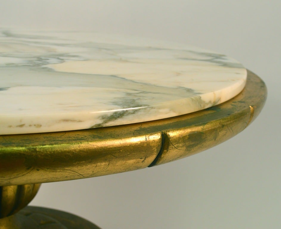 Round marble top coffee, cocktail table with gold gilt base. Base shows tarnishing as shown in pictures.  Design after James Mont, Hollywood Regency style Italian marble top.