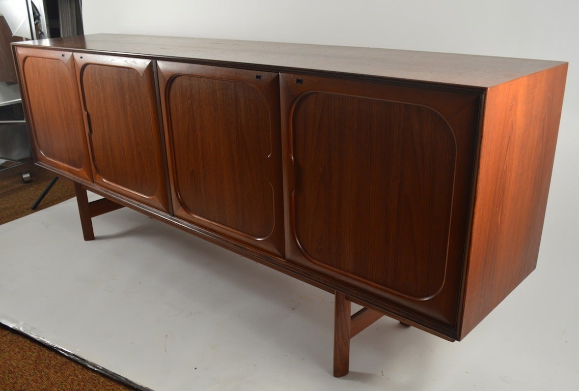Elegant and sophisticated teak credenza designed by Fredrik Kayser for Gustav Bahus. This sideboard features four locking doors, three of which open to revel adjustable shelves, one opens to drawers. Unusually long ( 83.75