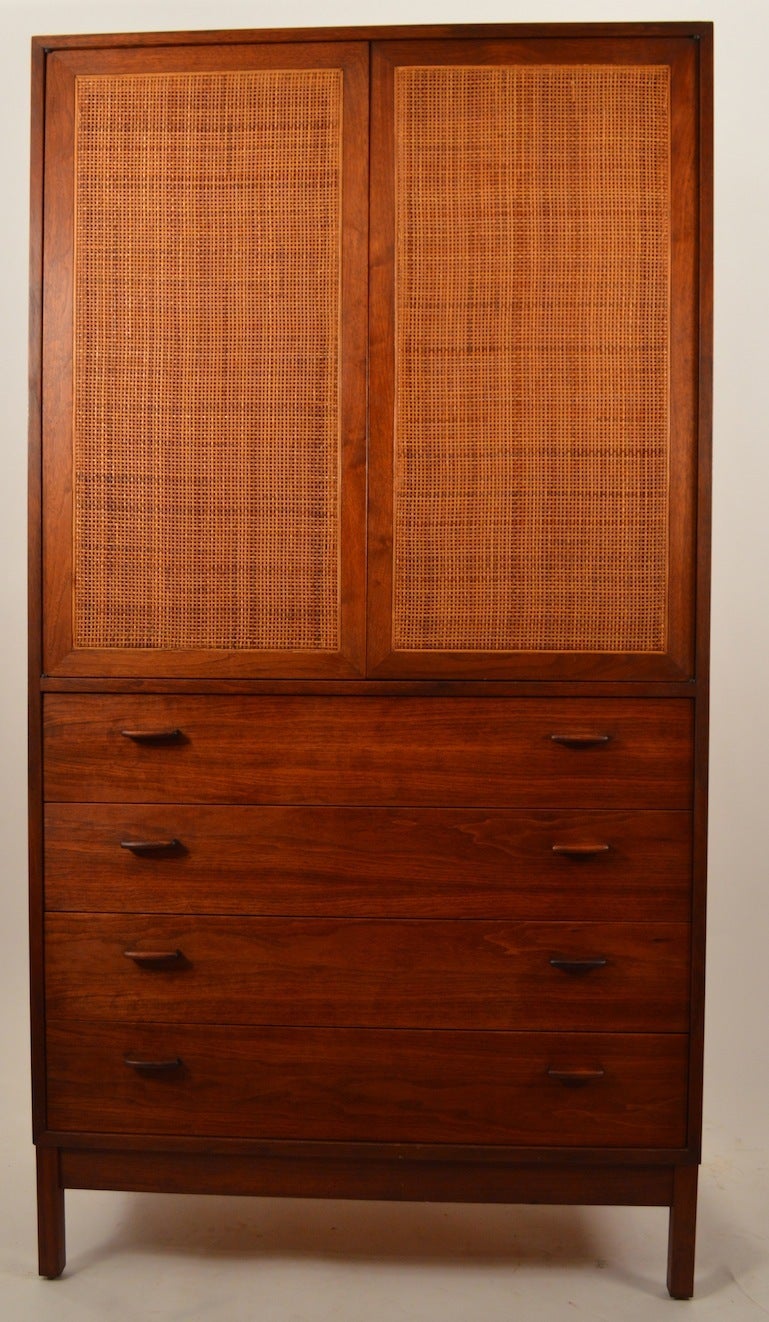 Interesting form Danish Modern Chifferobe with cane front doors which open to rosewood sock drawers, and white shirt plate slides, which adjust in position. The base consists of four drawers, this cabinet provides ample storage for your wardrobe.