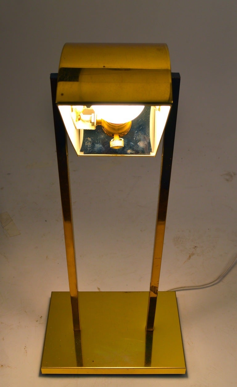 Adjustable brass desk lamp, with hood shade. The shade tilts up and down to direct the light to desired the  position. Classic sleek Art Deco Revival style, expected great Kovacs quality. This example has a small spot on the base plate,  it is in 