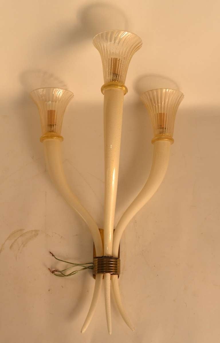 Elegant and impressive, pair of three light Murano Glass wall sconces. Cream color glass arms, with gold flack inclusion support clear glass trumpet shades, with gold flake inclusion.