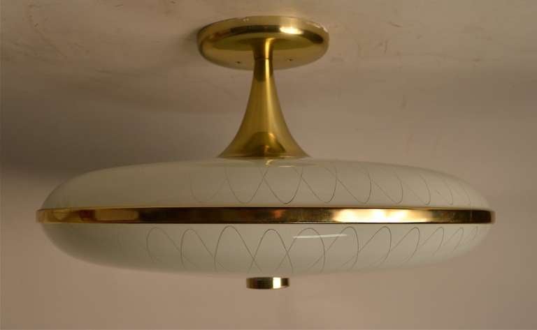 Glass top and bottom disk form chandelier with brass color aluminum hardware. Three bulbs illuminate the light fixture.