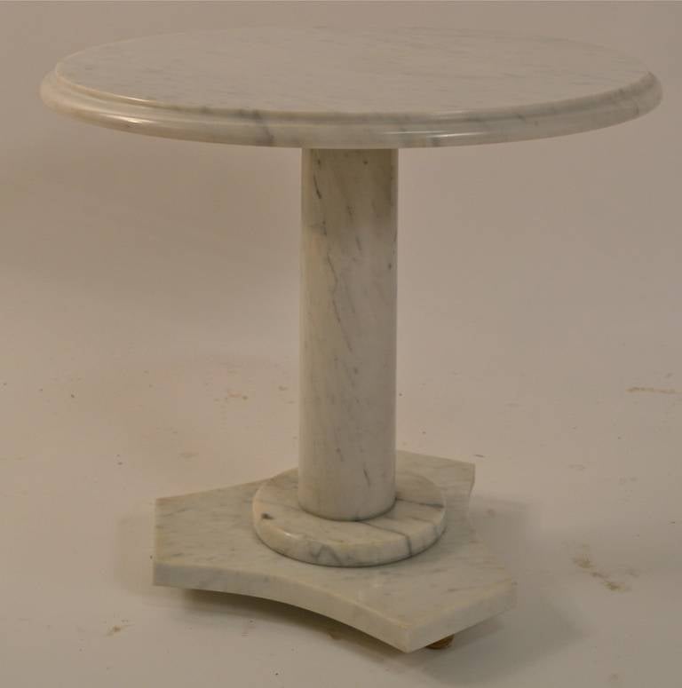 Polished white marble pedestal table, made in Italy. Classical form, round top supported by column pedestal, on a tri-part base, with round wood gold gilt feet. This example probably dates from the 1950's -1960's.