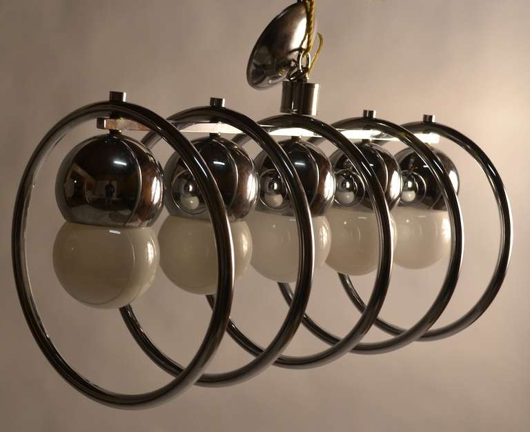 Circular chrome rings surround the large exposed bulbs, five lights make this chandelier capable of illuminating a large space. Bright chrome finish, fine original condition.