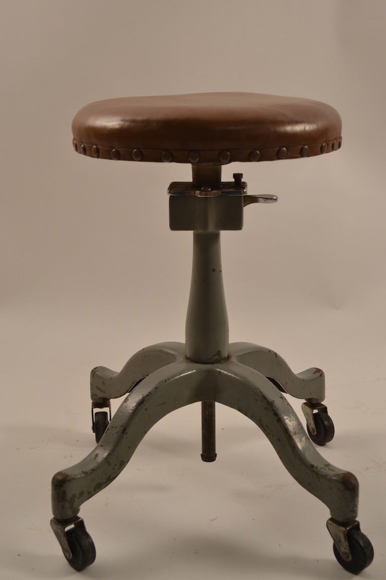 Heavy cast iron base, with original caster wheels, and upholstered pad seat. The stool will adjust in height ( Lowest 20.5