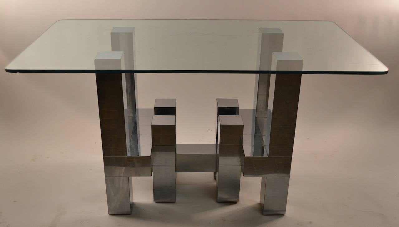 Chrome patchwork chrome square, and rectangular elements constitute the architectural base, the top is thick plate glass. The glass is as is,and probably should be replaced to suit your size requirements, the base will accommodate a larger, or