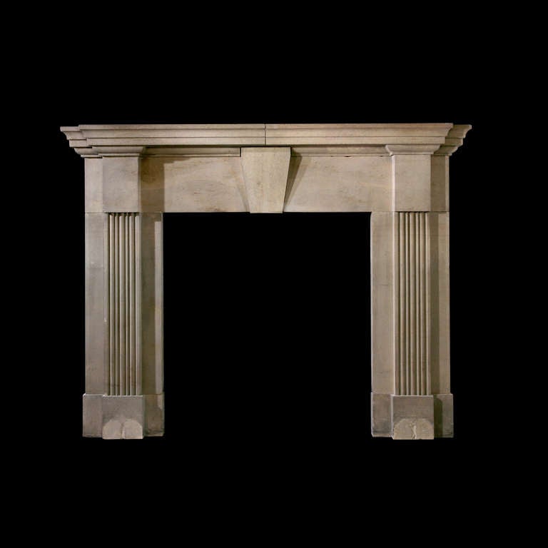 A large 19th century stone architectural mantel, the breakfront corniced shelf above a plain frieze with keystone and conforming corner blocks, the fluted jambs raised on block feet. Opening Dimensions: 45.75