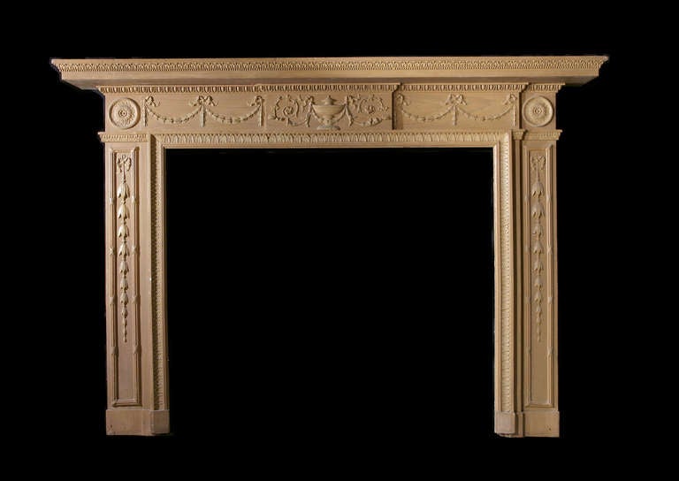 19th century pine and gesso mantel. The frieze panels feature bow tied swags and flank a center tablet with lidded tazza surrounded by foliate detail. The jambs feature ribbon tied bell drops under a corner block with circular paterae.
Opening