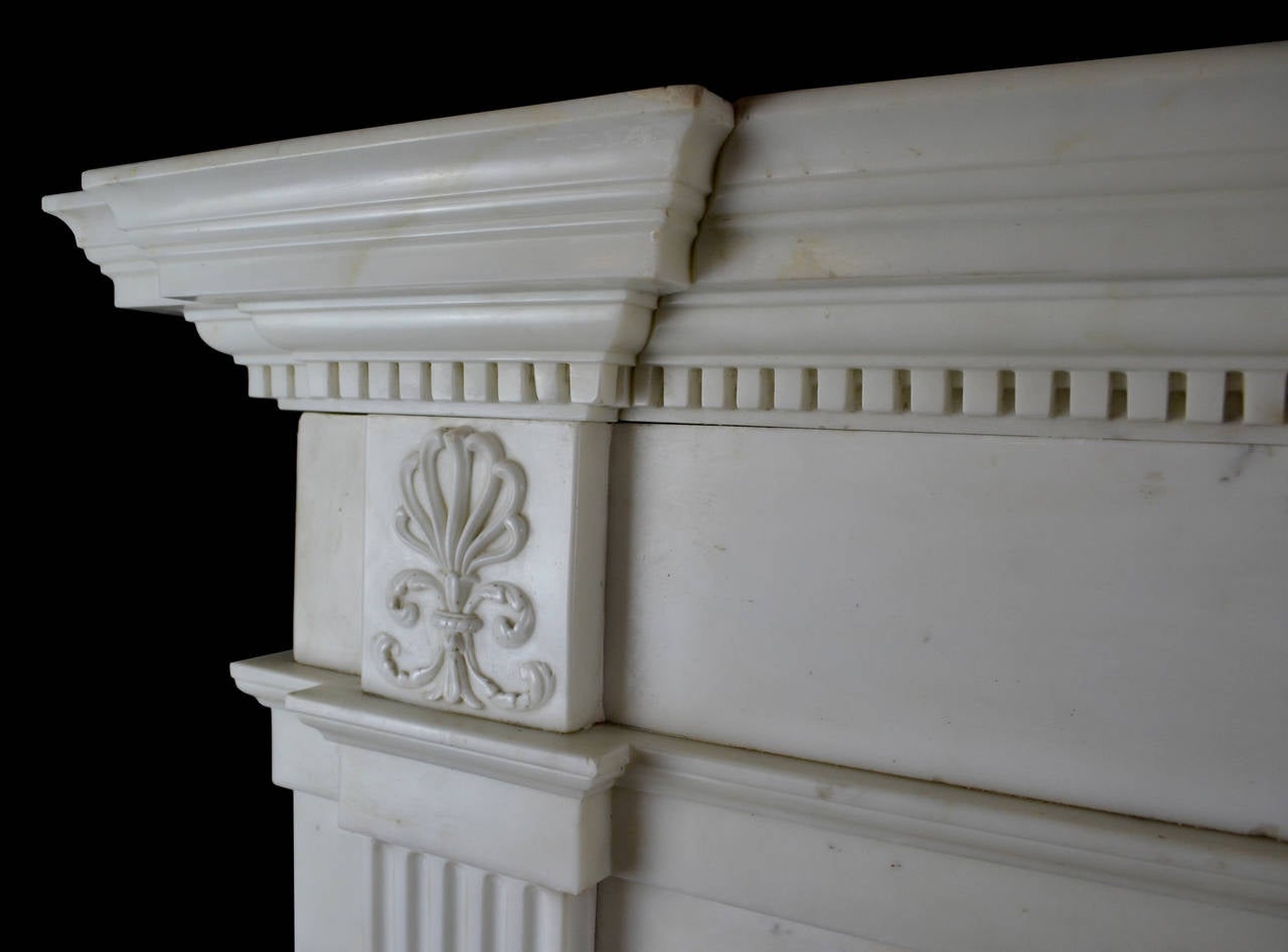 A very fine late 18th century statuary marble mantel of handsome proportions with breakfront corniced shelf incorporating a tier of dentil carving. The jambs have stop fluted tapering panels terminating beneath corner blocks carved with anthemion