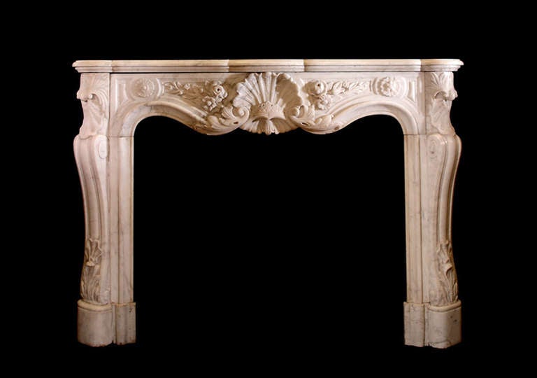 A 19th century French marble mantel in the Louis XV style with a paneled serpentine frieze and a central cartouche in the form of a sea shell flanked by rose foliate carvings.

    