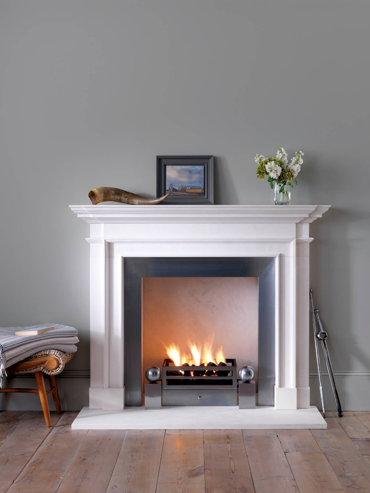 Classically proportioned limestone mantel with breakfront shelf.